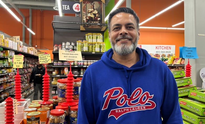 A man smiles at the camera in a grocery store