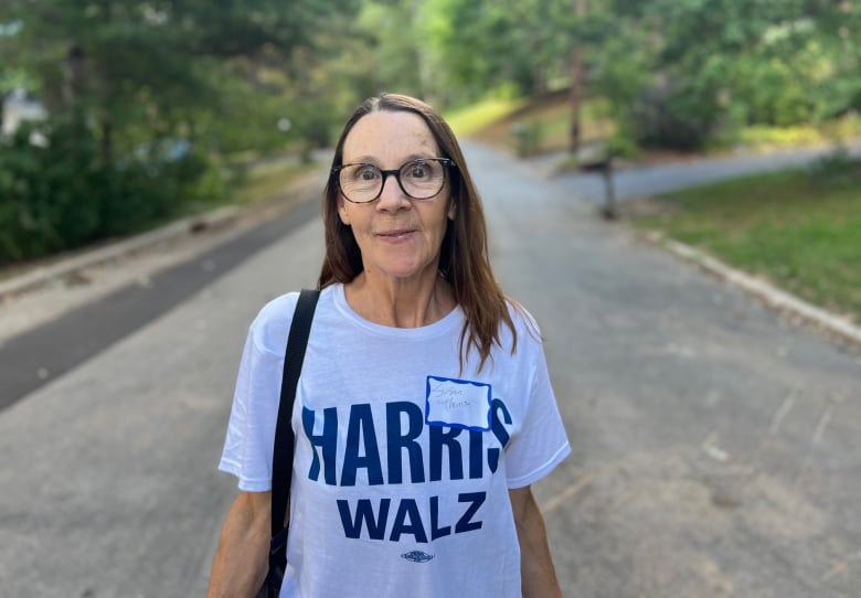 Woman walking on leafy road, wearing Harris-Walz T-shirt