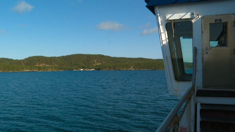 A white dock is shown in the distance while the control room of a ferry is seen on the left of the photo