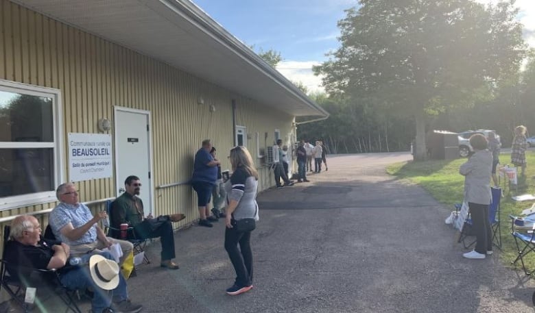 People sit and stand outside a building.