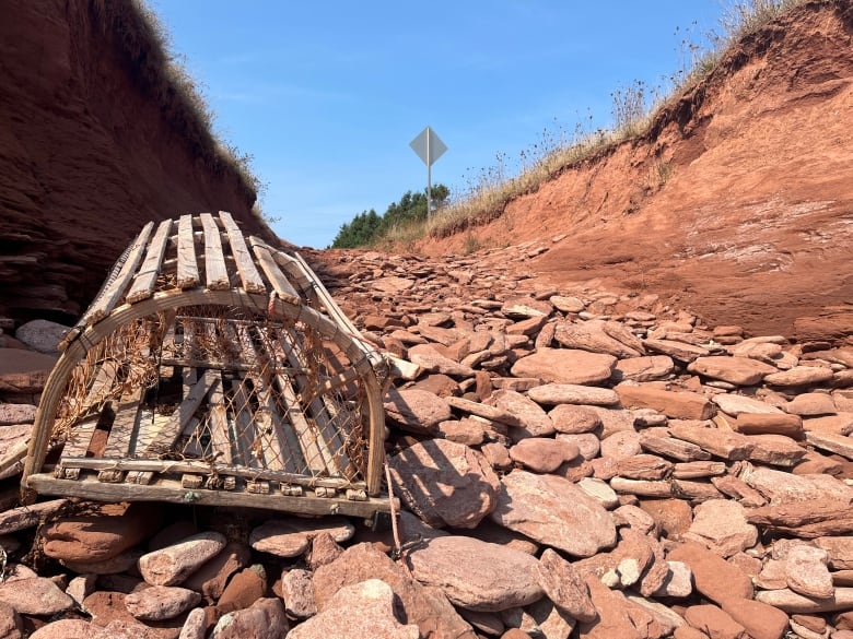 A lobster trap in the foreground of a path leading to a red sand beach near Tignish, PEI.