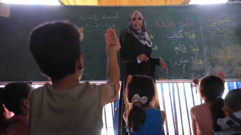 A woman stands at a chalkboard in front of students