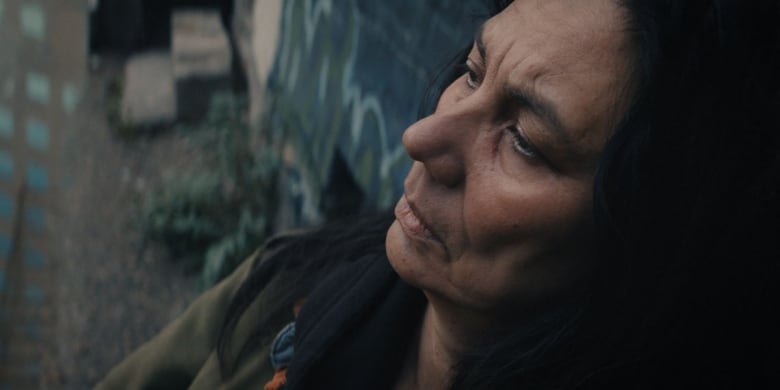 A still from a film shows a closeup of a woman staring ahead.