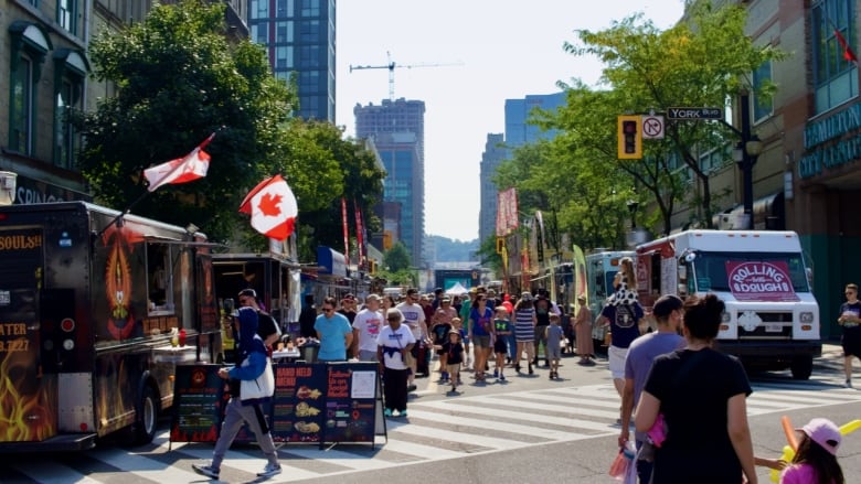 A crowd of people fill a downtown city street. 