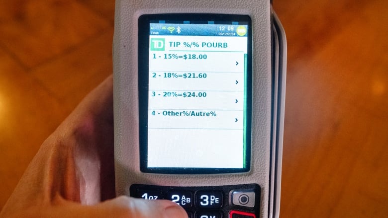 A payment terminal displays tip options at a restaurant