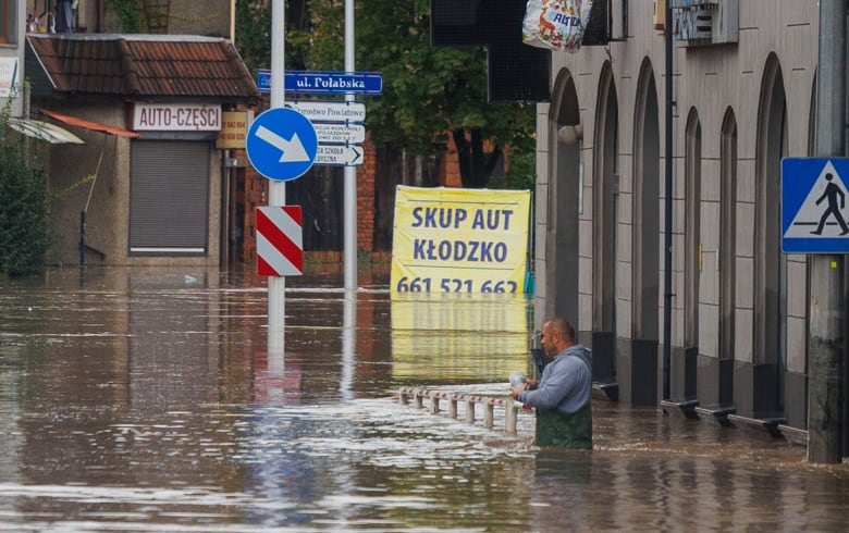 A man stands in waist-deep floodwaters.