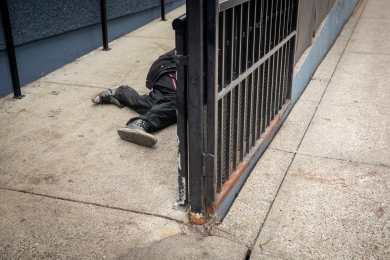 A person's shoes are pictured on a ramp on a sidewalk.