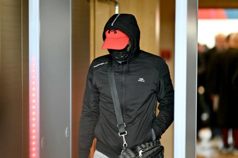 A man wears a bandana to cover his face entering a court