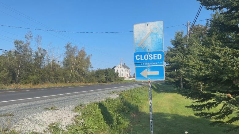 a blue sign with a key icon says closed along a rural highway. 