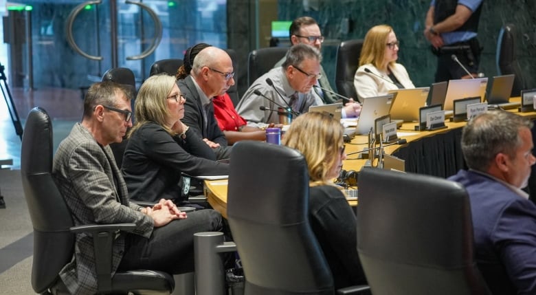 A group of people sit around a curved desk