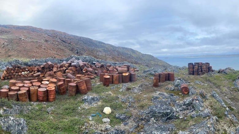 Dozens of rusting fuel drums are stacked on a hillside in northern Que. 