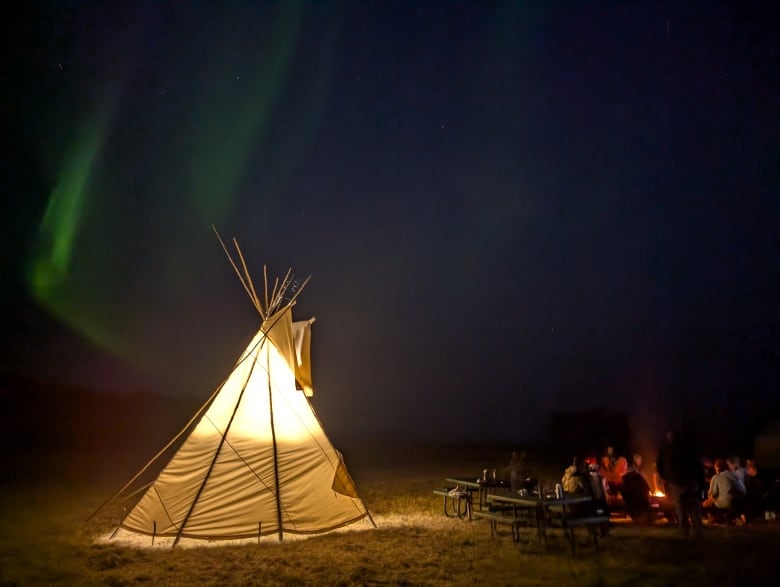 A tipi glows under the northern lights 