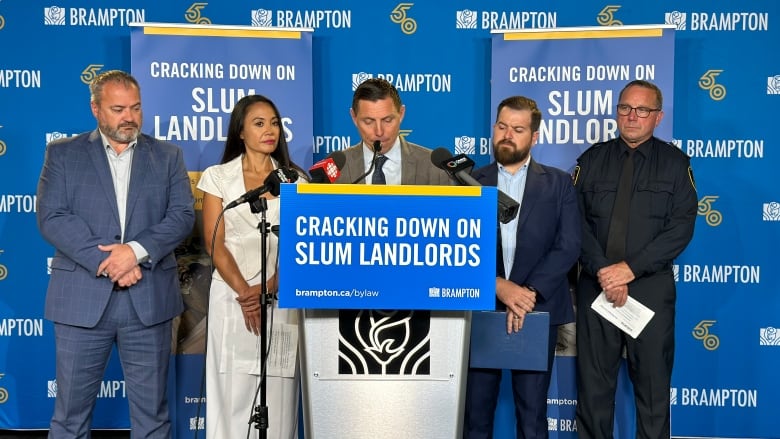 Five people standing behind a podium 