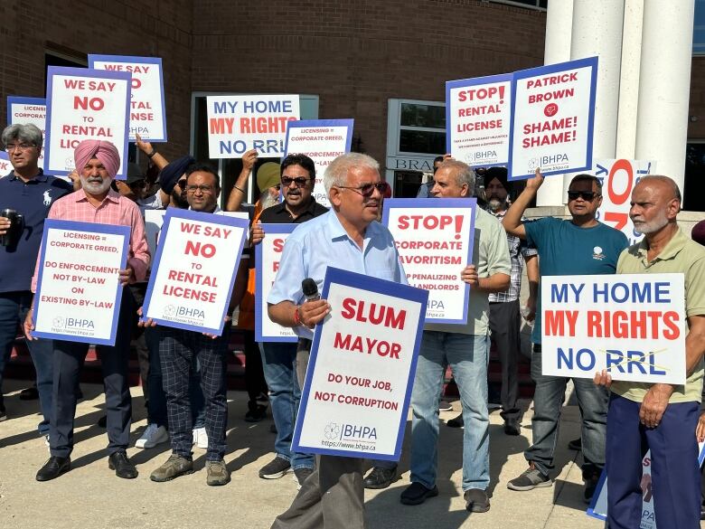 Men standing with protest banners outside a building