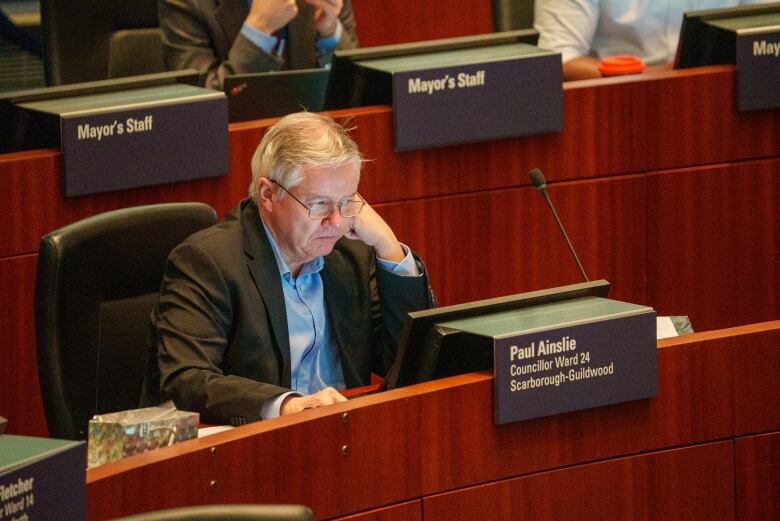 Man looks a screen, resting his chin on his hand.