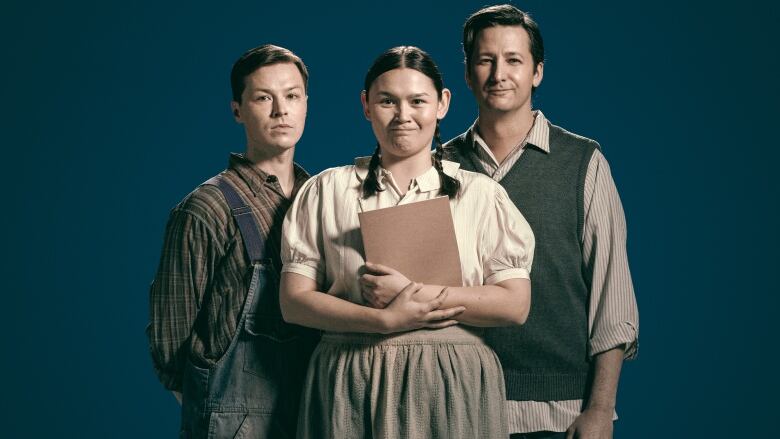 Indigenous actors in character pose looking at camera. Two men and one woman, they're dressed in 1930s style clothes.