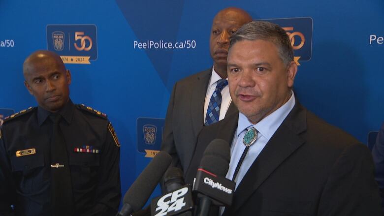 Albuquerque Police Chief Harold Medina standing in front of a blue backdrop and addressing the media at the conference