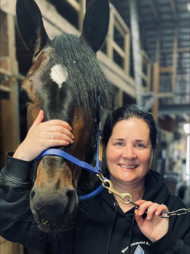 A woman stands with a horse 