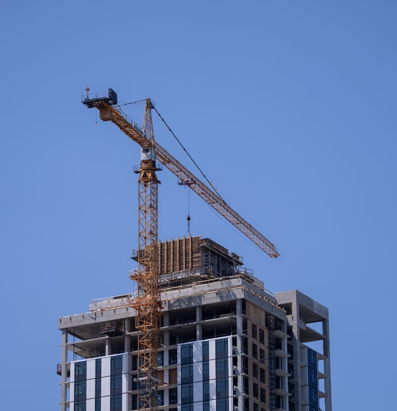 A crane is seen next to a tall apartment building.