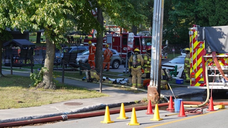 Firefighters and trucks seen parked on a street. 