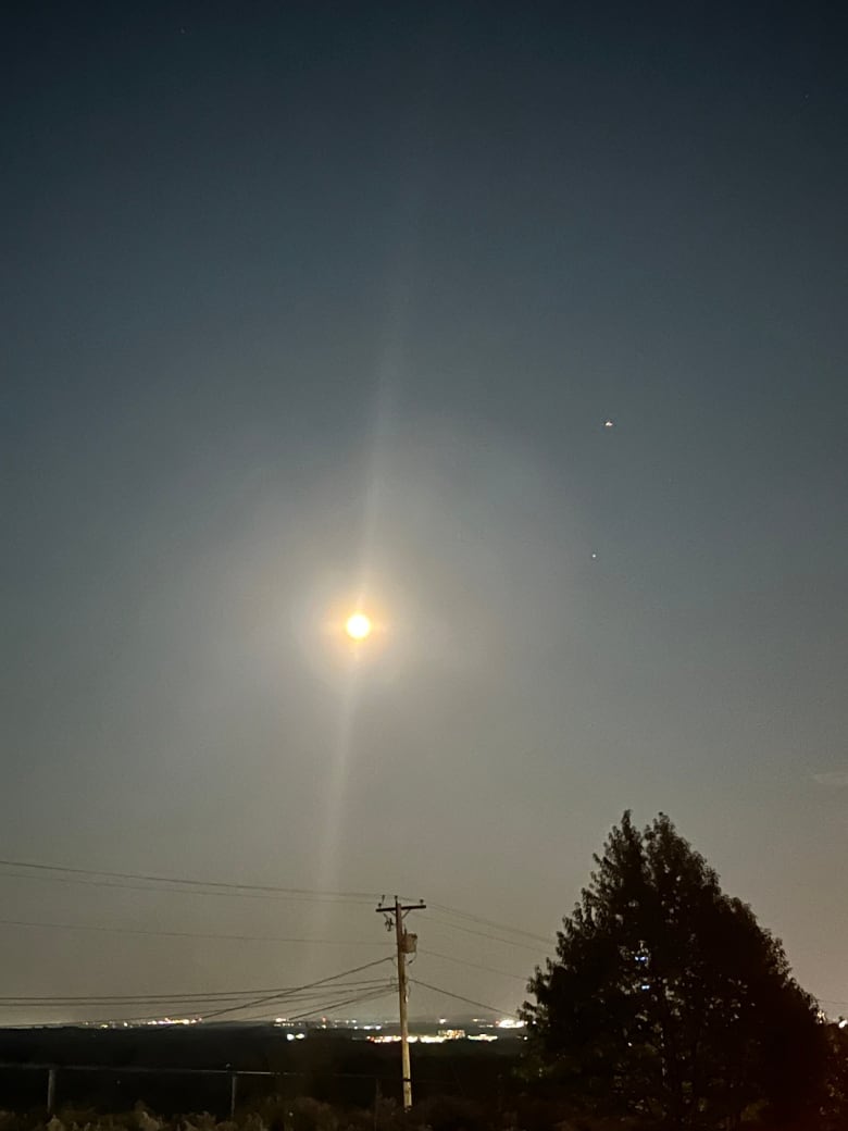 A full moon shines over a city.