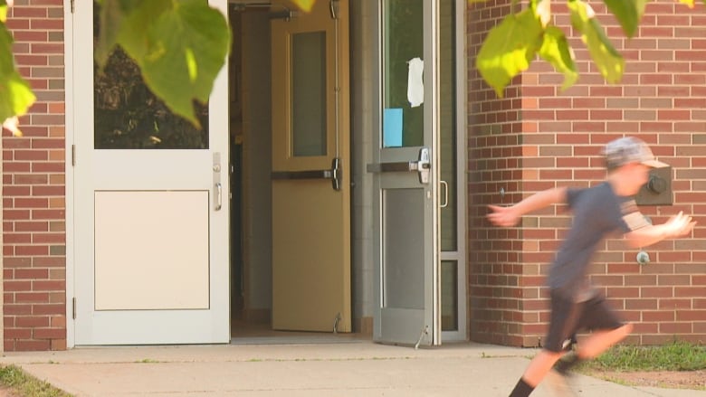 Boy running past open door at school.