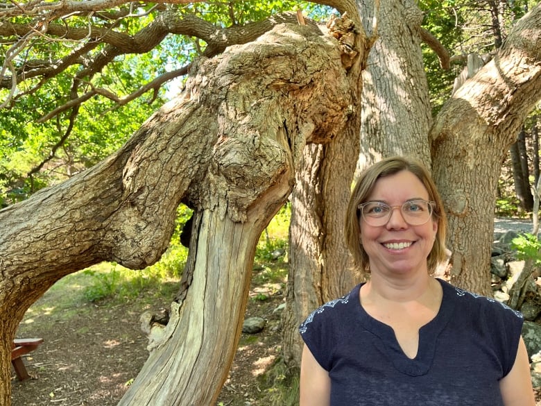 A woman standing near an oak tree. She is smiling.