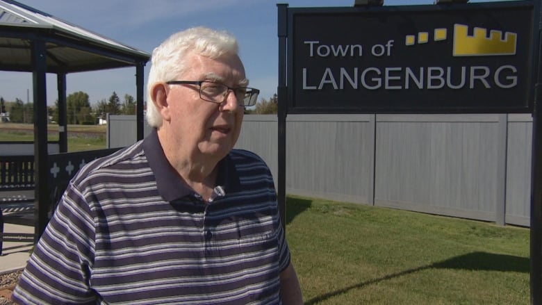 Man standing in front of town sign of Langenburg. 