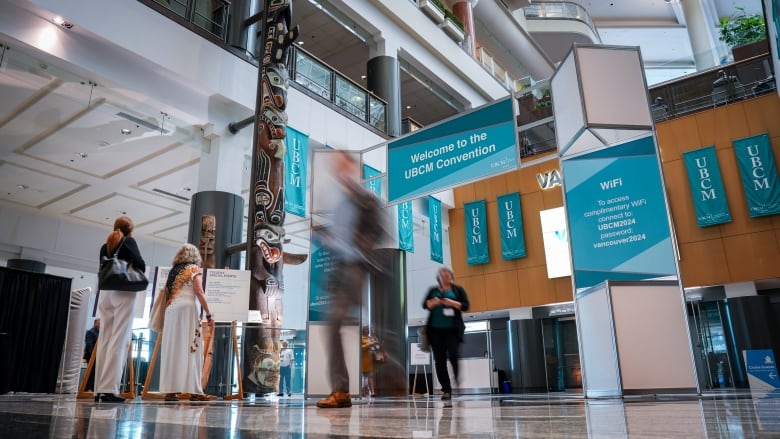 A convention centre with people coming and going with UBCM signage.