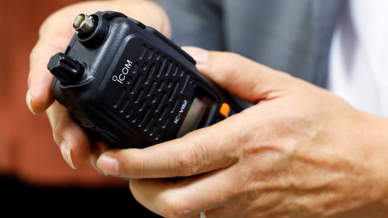 A close-up on hands holding a radio. 