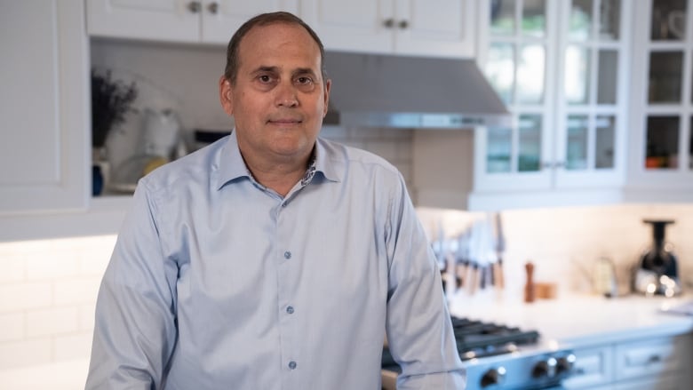 Warren Kotler, a man in his sixties, stands in his kitchen.