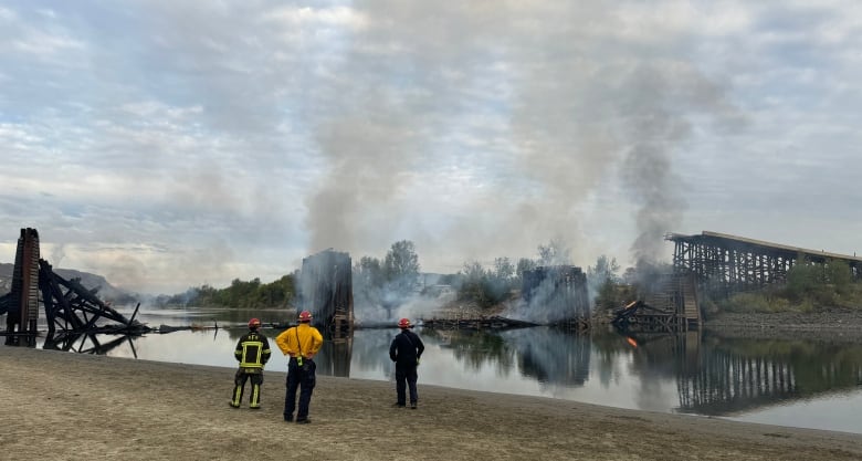 Firefighters stand on the bank of the South Thompson River. 