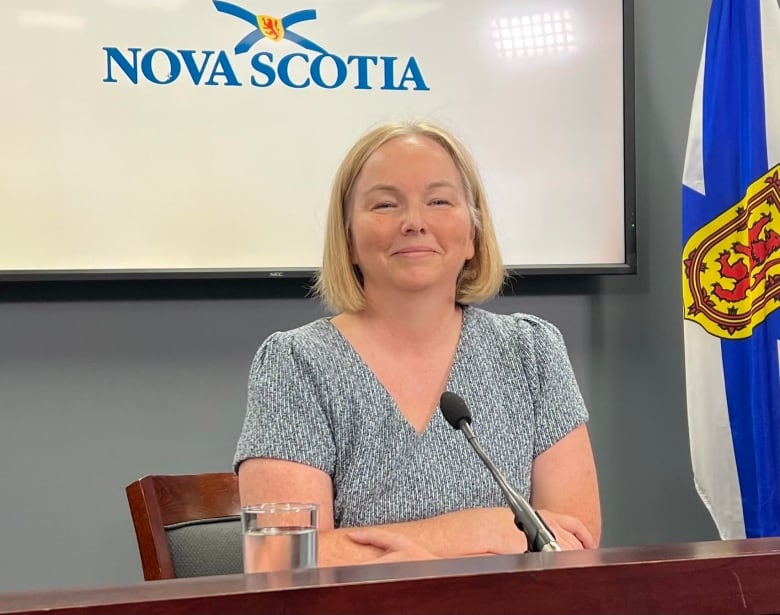 Woman sits at desk near a Nova Scotia flag