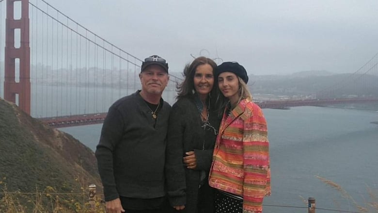 A man and two women standing in front of the Golden Gate Bridge in cloudy weather. 