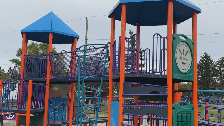 A climbing tower built from bright orange and purple metal bars and other brightly coloured materials.