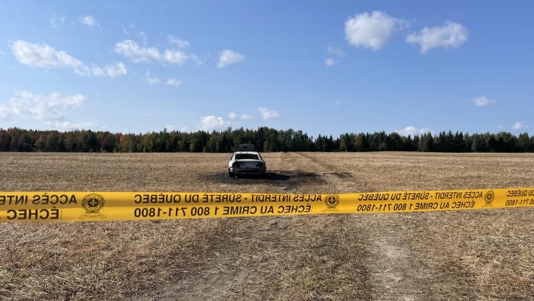 burnt out car in the middle of a field. 