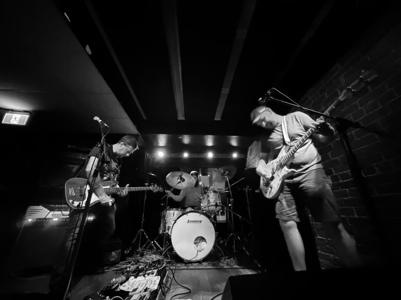 A black and white photo of a band playing on a small stage