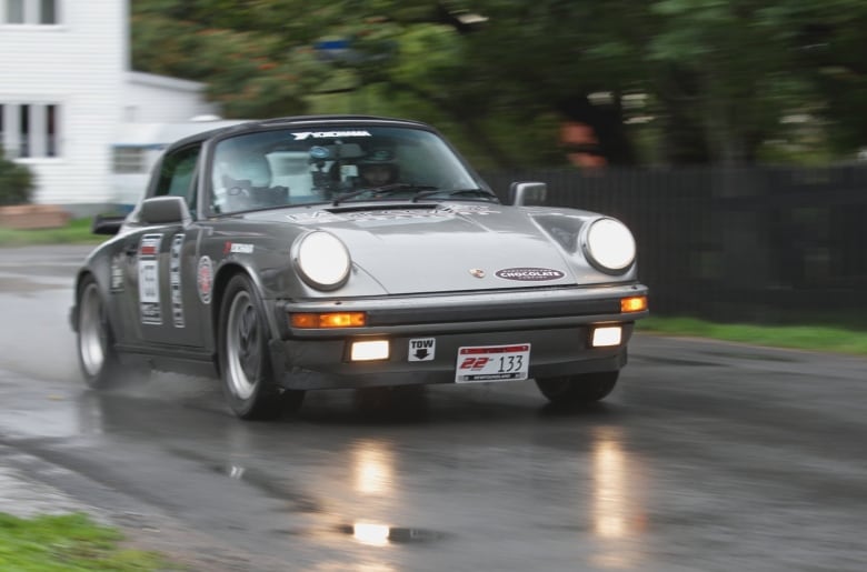 A race car splashes through water on a quiet residential street. 