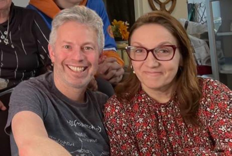 A man and woman sit side by side, smiling for the camera. 