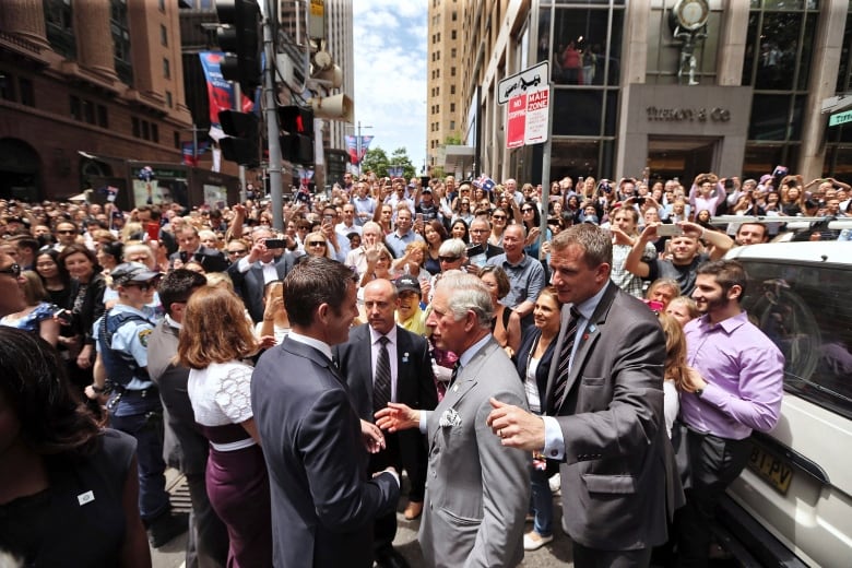 A large crowd fills a street between tall buildings.