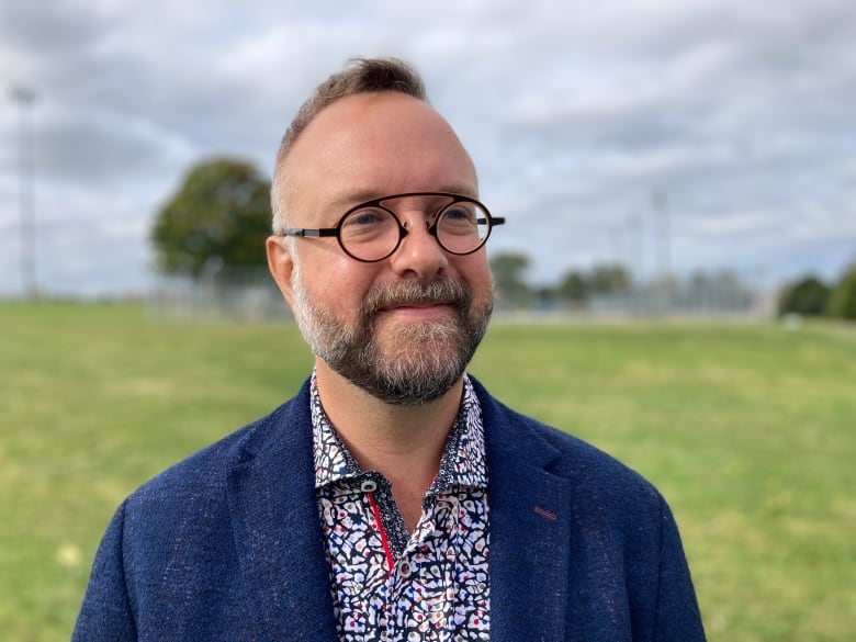 A smiling man with circular glasses