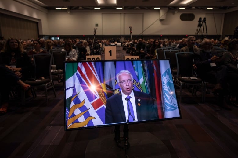 John Rustad on a screen in front of delegtes