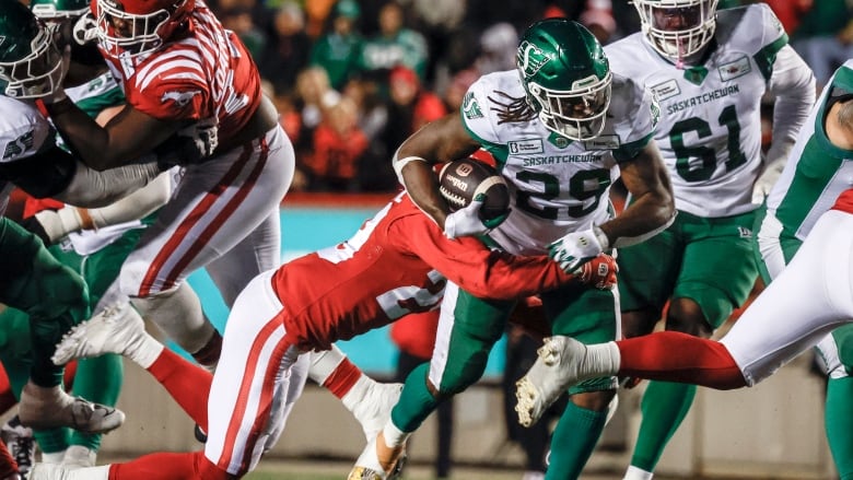 Ryquell Armstead is busting through a group of calgary players while holding the ball