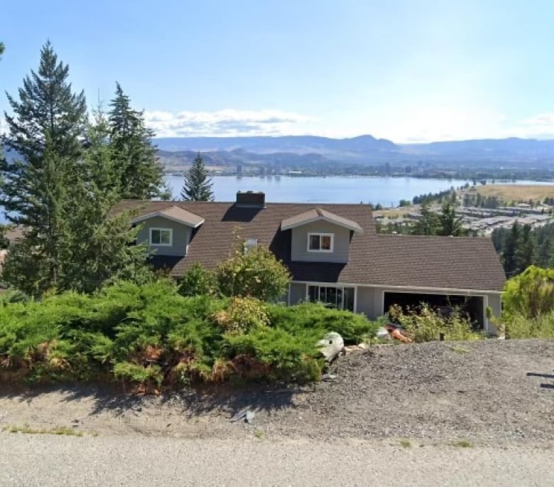 A picture of a home next to a picturesque mountain and lake.