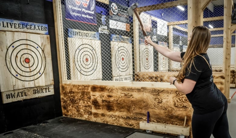 A woman throws an axe at a target.