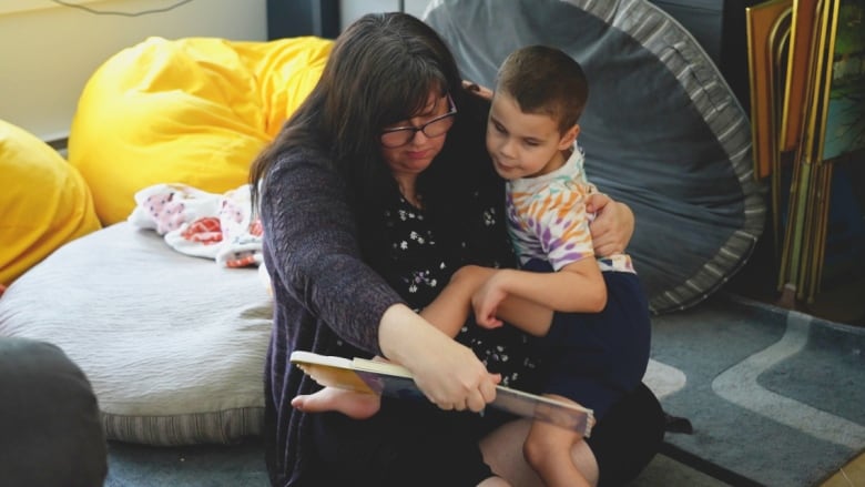 Daniel and his mom, Ashley, at home, reading together on the floor. 