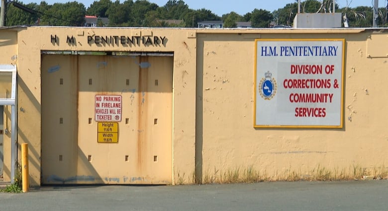 Yellow concrete wall with large door that says H.M. Penitentiary