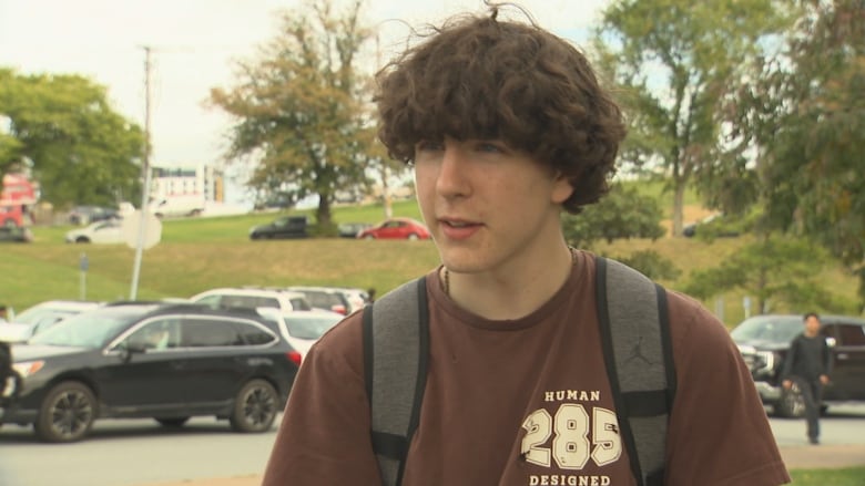 A teenage boy wearing a brown t-shirt is looking at the camera doing an interview outside a school in Halifax, N.S.