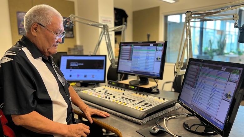 A man sits in a radio station control room. 