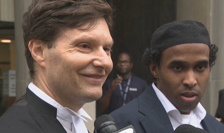 Criminal defence lawyer Gary Grill and his client Hassan Ali speak to reporters outside the courthouse on Monday. 